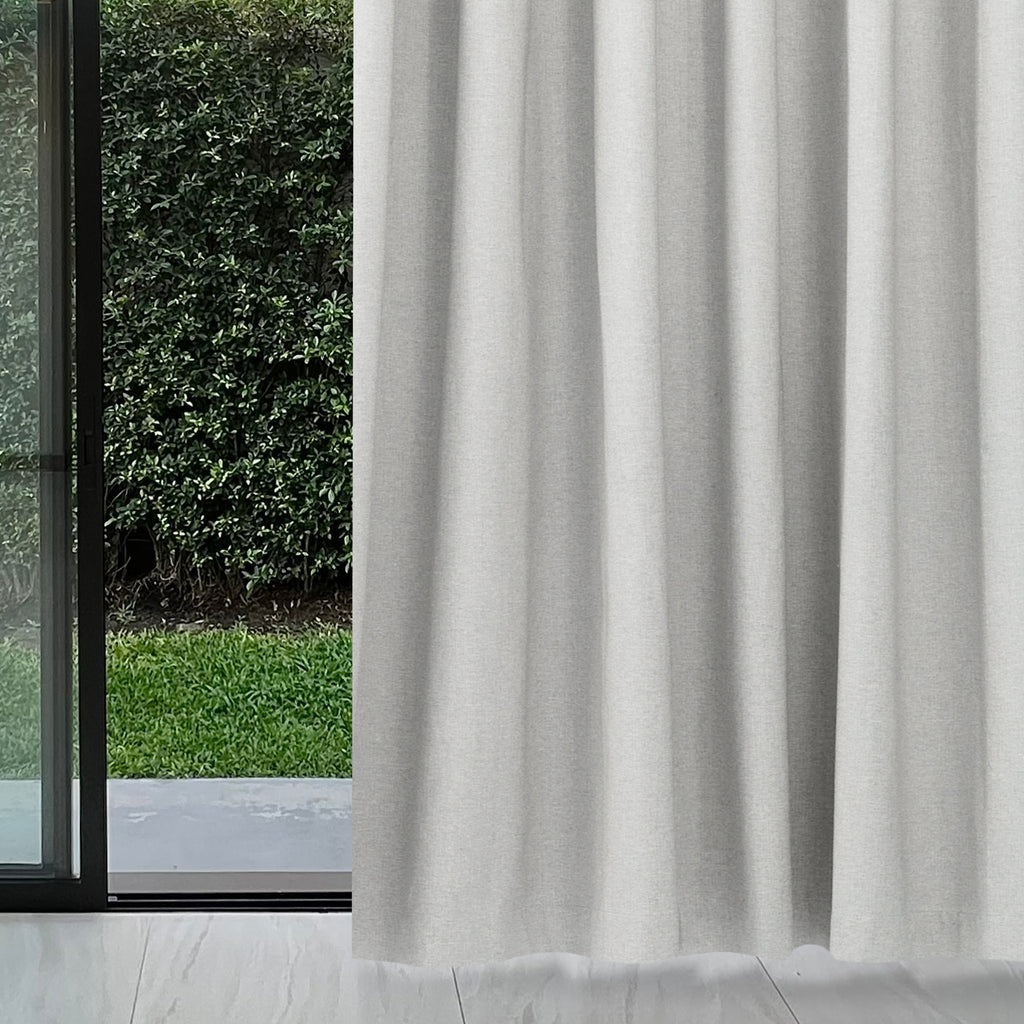 Pearl grey Dakota block out curtain beside a sliding glass door with a garden view