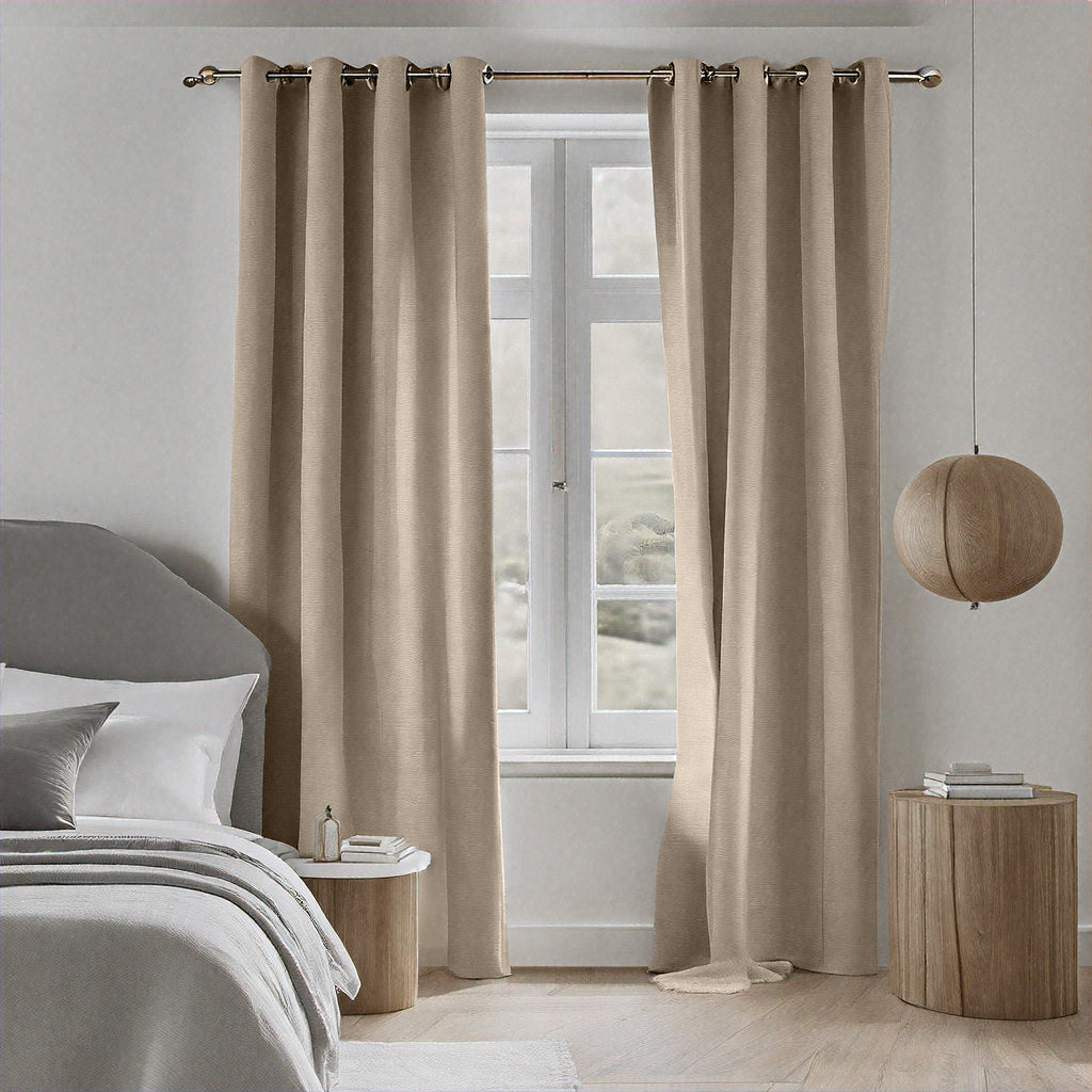 Almond Dakota block out curtains framing a bedroom window beside a bed with a wooden nightstand