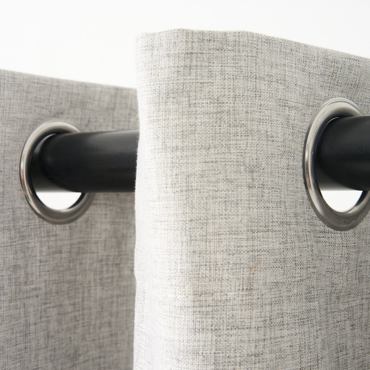 Close-up of the eyelet grommets on the Sinclair curtain in creme grey, threaded onto a curtain rod